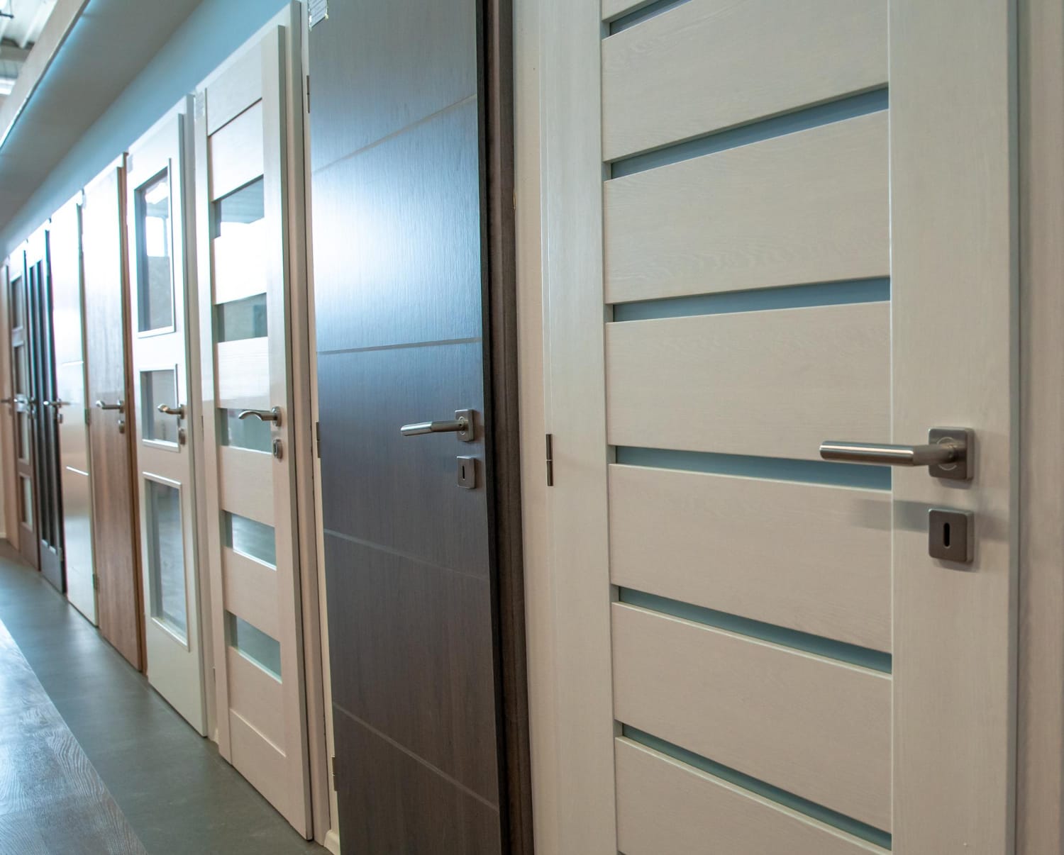 Row of commercial interior doors with lever handles and glass lites on display